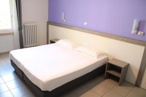 a bed in a room with a purple wall at Hotel Savoia in Poggio Rusco