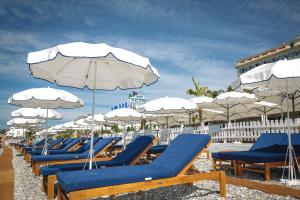 a row of lounge chairs and umbrellas on a beach at Hotel Aston La Scala in Nice