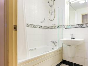 a white bath tub sitting next to a white sink at Kegworth Hotel & Conference Centre in Castle Donington