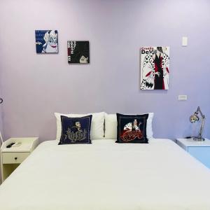 a bedroom with a white bed with four pictures on the wall at 唐揚十二街 in Tainan