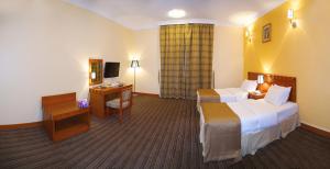 a hotel room with two beds and a desk at Al Massa Plus Hotel in Al Ain