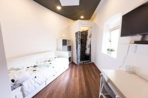 a white bedroom with a bed and a television at Rooms Viktorin in Ptuj