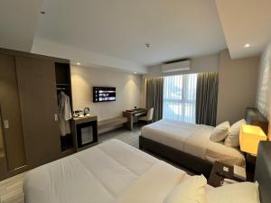 una camera d'albergo con due letti e una televisione di Capitol Hill Hotel and Suites a Angeles