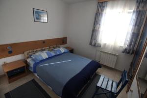 Schlafzimmer mit einem Bett mit blauer Bettwäsche und einem Fenster in der Unterkunft Apartments by the sea Zlarin - 14025 in Zlarin