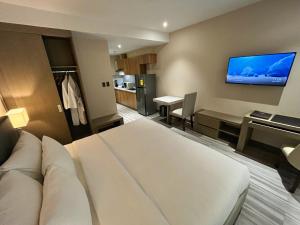 アンヘレスにあるCapitol Hill Hotel and Suitesのベッドと壁にテレビが備わるホテルルームです。