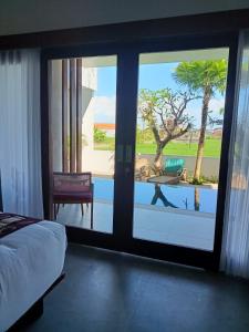 a bedroom with a sliding glass door with a view of a patio at The Kd Suites & Coffee Shop in Munggu