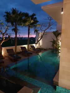 a pool at night with palm trees and chairs at The Kd Suites & Coffee Shop in Munggu