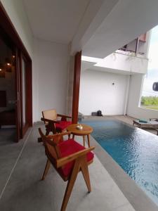 a living room with a pool and chairs and a table at The Kd Suites & Coffee Shop in Munggu