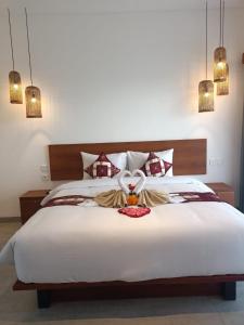 a bedroom with a large white bed with a stuffed animal on it at The Kd Suites & Coffee Shop in Munggu