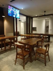 a room with wooden tables and chairs and a flat screen tv at The Kd Suites & Coffee Shop in Munggu