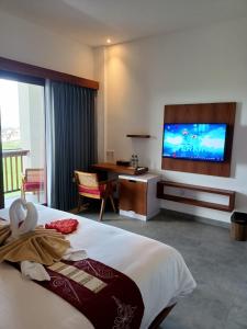 a hotel room with a bed and a flat screen tv at The Kd Suites & Coffee Shop in Munggu