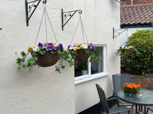a patio with flower baskets hanging from a building at 4 Bedroom townhouse on one of the oldest streets in Wymondham