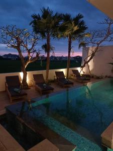 a swimming pool with chaise lounge chairs and palm trees at The Kd Suites & Coffee Shop in Munggu