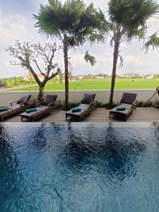 a pool with chaise lounge chairs and palm trees at The Kd Suites & Coffee Shop in Munggu