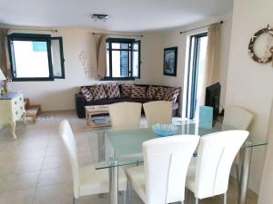 a living room with a glass table and white chairs at Villa ioli breathtaking view & sunset in Agios Nikitas