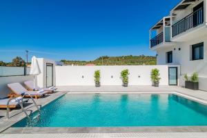 uma piscina com cadeiras ao lado de um edifício em Eagle's Nest - Adjoining Villas! em Tsilivi