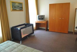 um quarto com uma televisão, uma cama e um armário em Auberge Gaglioti em Luxemburgo