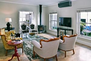 a living room with chairs and a table and a tv at Le Petit Bijou Boutique Apartments - Solar Power in Franschhoek