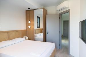 a bedroom with a white bed and a mirror at Villa Alexia in Pefkohori