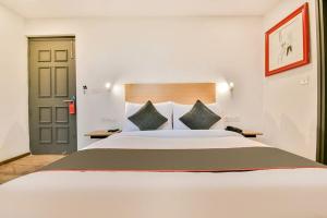 a bedroom with a large white bed with green pillows at Hotel Broadway Udaipur in Udaipur
