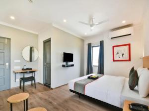 a bedroom with a bed and a desk and a television at Hotel Broadway Udaipur in Udaipur