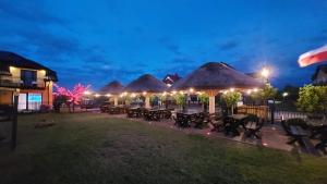a group of tables with thatched roofs at night at Willa Kwiatano - Plac zabaw & Jacuzzi & Basen & Sauna in Grzybowo