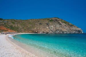 a beach with blue water and a hill in the background at Andros Melissari in Koumárion