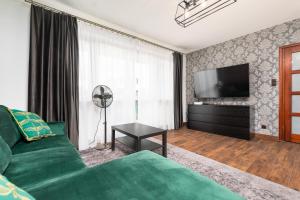 a living room with a green couch and a flat screen tv at Sokratesa 2B by Homeprime in Warsaw
