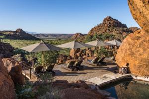 een man op een houten brug met parasols en stoelen bij Mowani Mountain Camp in Khorixas