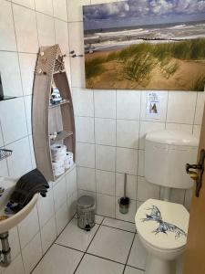 een badkamer met een toilet en een schilderij aan de muur bij Minsener Warft in Wangerland