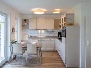 a kitchen with white cabinets and a table and chairs at Darßer Weg FW 9 in Zingst