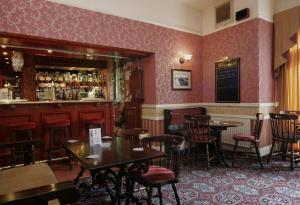 a restaurant with tables and chairs and a bar at Eskdale Lodge in Sale