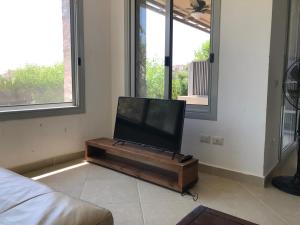 einbay 3 bedrooms garden + pool view في العين السخنة: تلفزيون بشاشة مسطحة جالس على طاولة في غرفة المعيشة