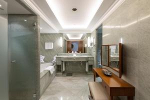 a bathroom with a shower and a sink and a tub at Suvretta House in St. Moritz