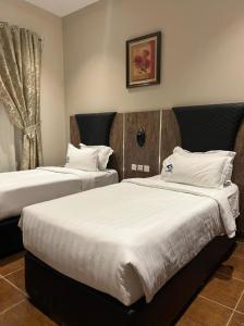 1 dormitorio con 2 camas con sábanas blancas y ventana en Hotel & Resort Golden Marina Yanbu, en Yanbu