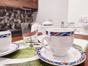 two cups and plates on a table with a glass at Alchemilla Holiday Home in Salerno