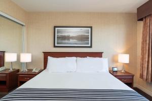 a large bed in a hotel room with two lamps at Sandman Suites Surrey - Guildford in Surrey