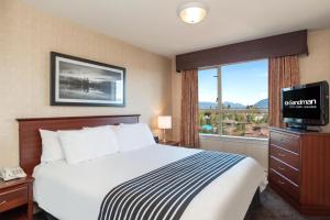 a hotel room with a bed and a window at Sandman Suites Surrey - Guildford in Surrey