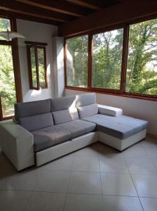 sala de estar con sofá grande y ventanas en Casa dei Faggi, en Tolfa