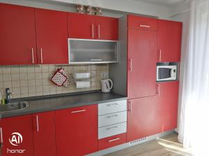 uma cozinha com armários vermelhos e um micro-ondas em Family apartment B&B em Biograd na Moru