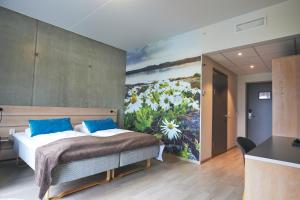 a bedroom with a bed with a painting on the wall at Hjorten Hotell Hitra in Fillan