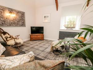 uma sala de estar com uma televisão e um sofá em The Old Byre em Falmouth