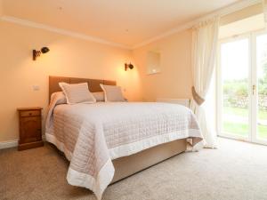 um quarto com uma cama e uma grande janela em The Old Byre em Falmouth