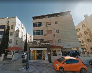 an orange car parked in front of a building at Lovely Two Bedroom Apartment in Amman in Umm Uthainah