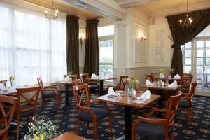 a restaurant with wooden tables and chairs and windows at Old Hunstanton Le Strange Arms Hotel in Hunstanton