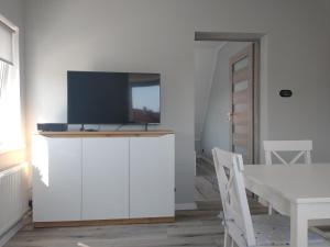 a living room with a tv on top of a white cabinet at Stara Oliwa in Gdańsk