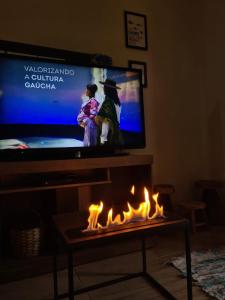 sala de estar con TV y chimenea con llamas en MARÉ 2 - brisa do mar en Tramandaí
