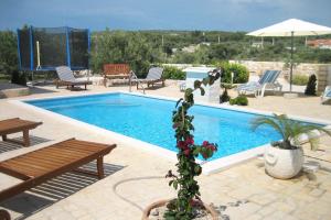 een zwembad met stoelen en een bank en een plant ernaast bij Family-friendly apartments with swimming pool Dvornica, Rogoznica - 11470 in Rogoznica