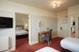 a hotel room with two beds and a desk with a mirror at Old Hunstanton Le Strange Arms Hotel in Hunstanton
