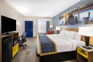 a hotel room with a bed and a flat screen tv at Days Inn & Suites by Wyndham Savannah Midtown in Savannah